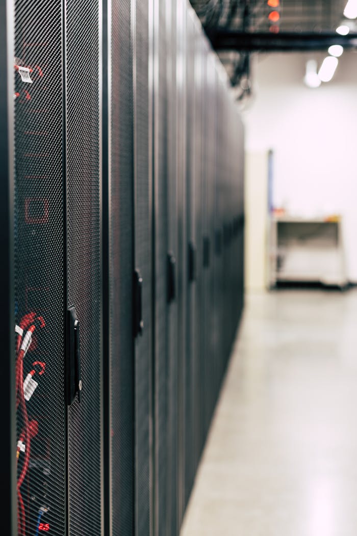 creative-02 Metal black cabinets with servers inside with red wires connected standing in row in lighted room